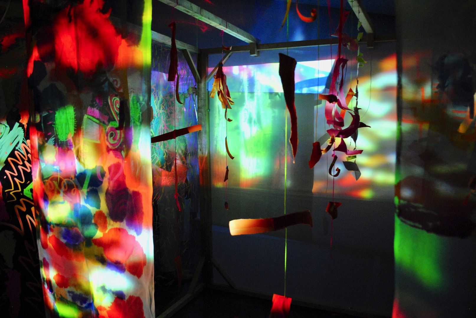 Installation view of a dark space with lots of different coloured light projections.