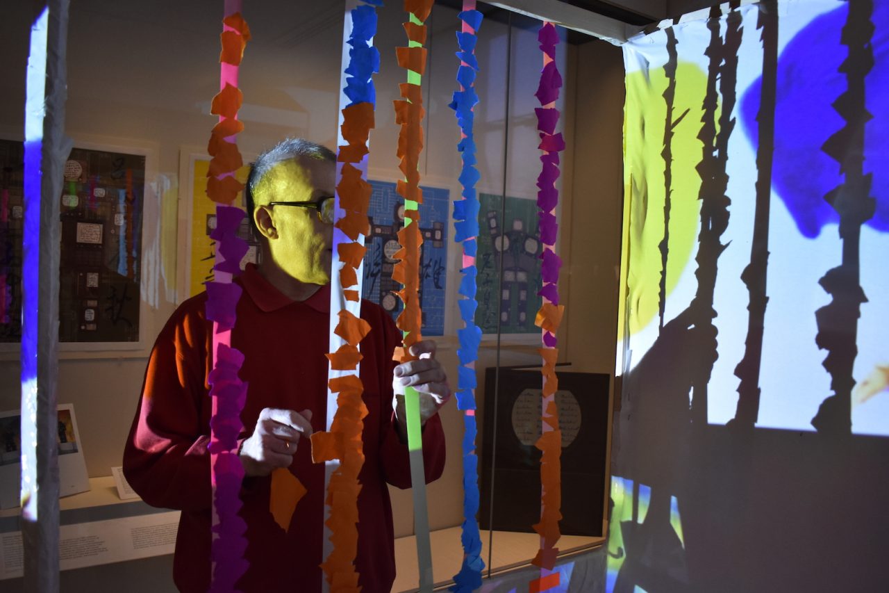 Artist Mark Lawrence adding paper and tape to an artwork as part of a live art event.