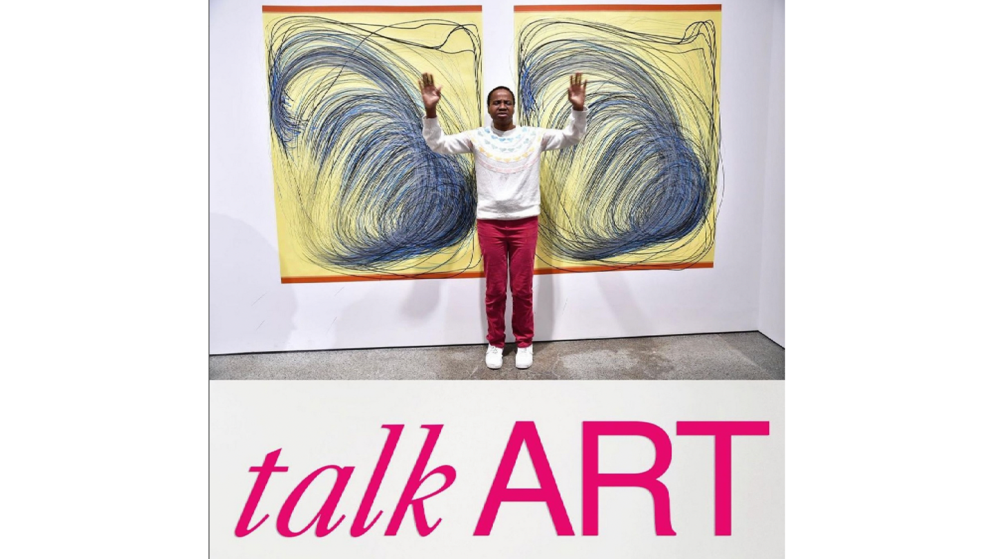 Nnena Kalu standing between two of her artworks displayed on a wall