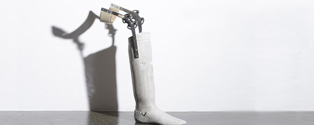 A white prosthetic leg placed against a white wall.
