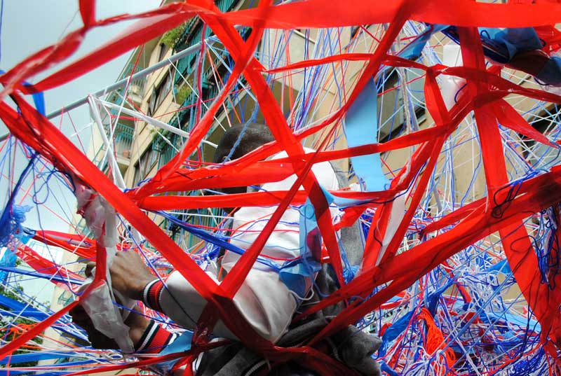 A man working on an art installation made of blue and red coloured tape and yarns.