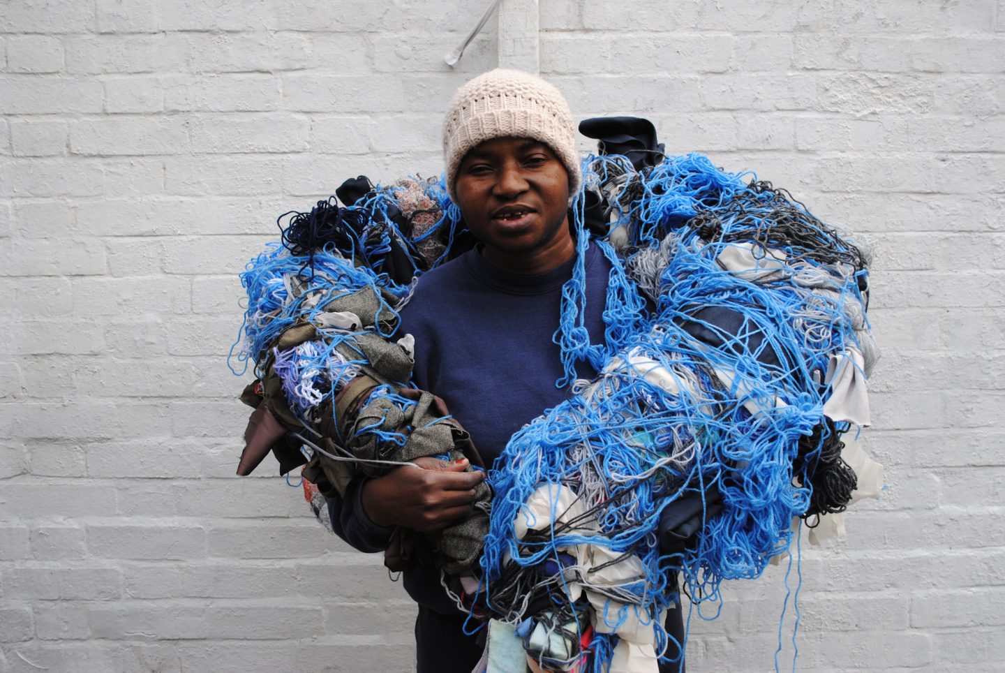 Artist Nnena Kalu holding one of her sculptures over her shoulders.