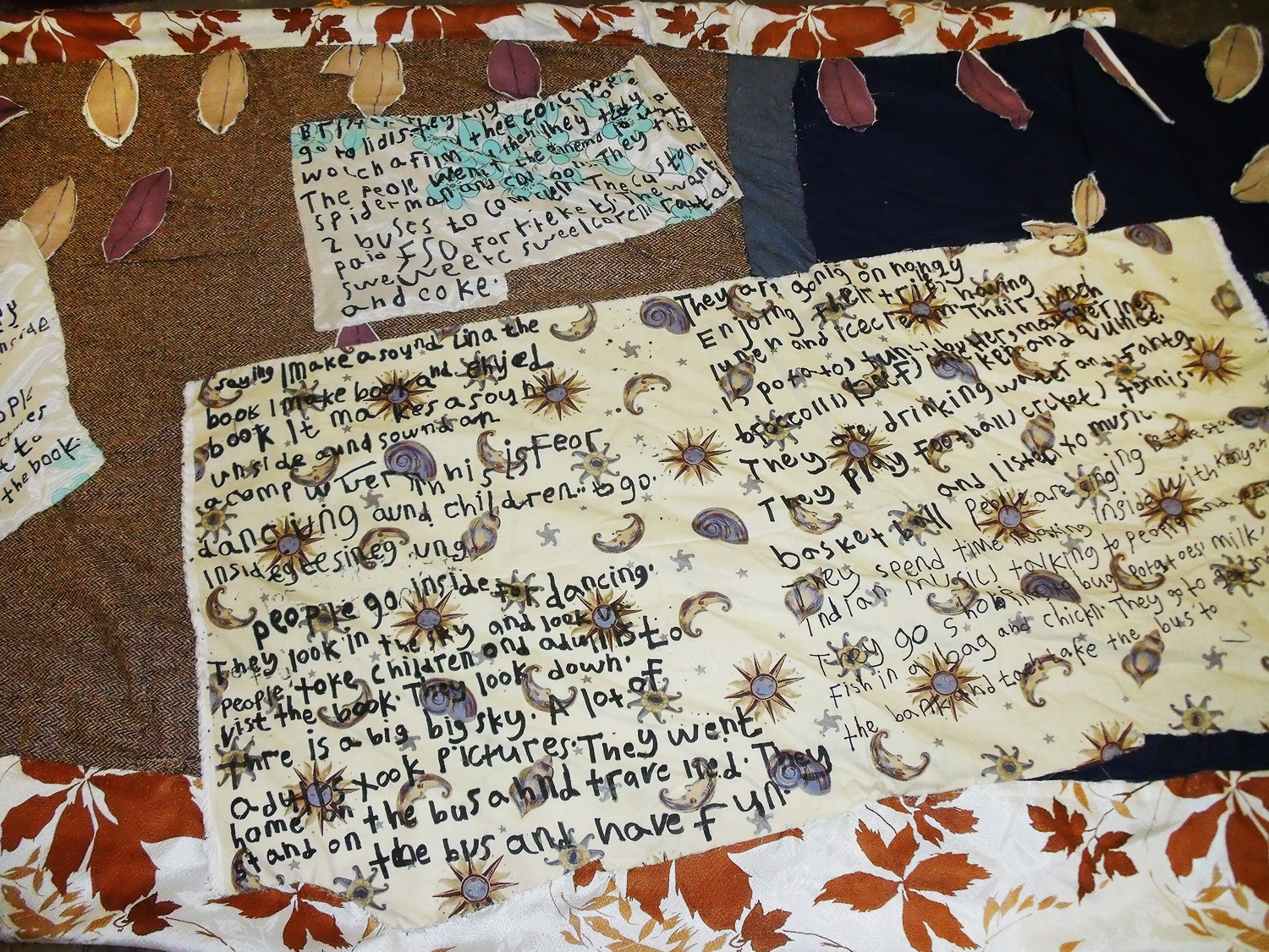 Andrew's writing ona. large piece of paper, with moons, shells and stars on the background of the paper.
