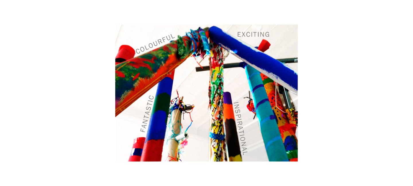 A close up photograph of an installation made of tall painted cardboard tubes with the words "colourful, exciting, fantastic, inspirational".