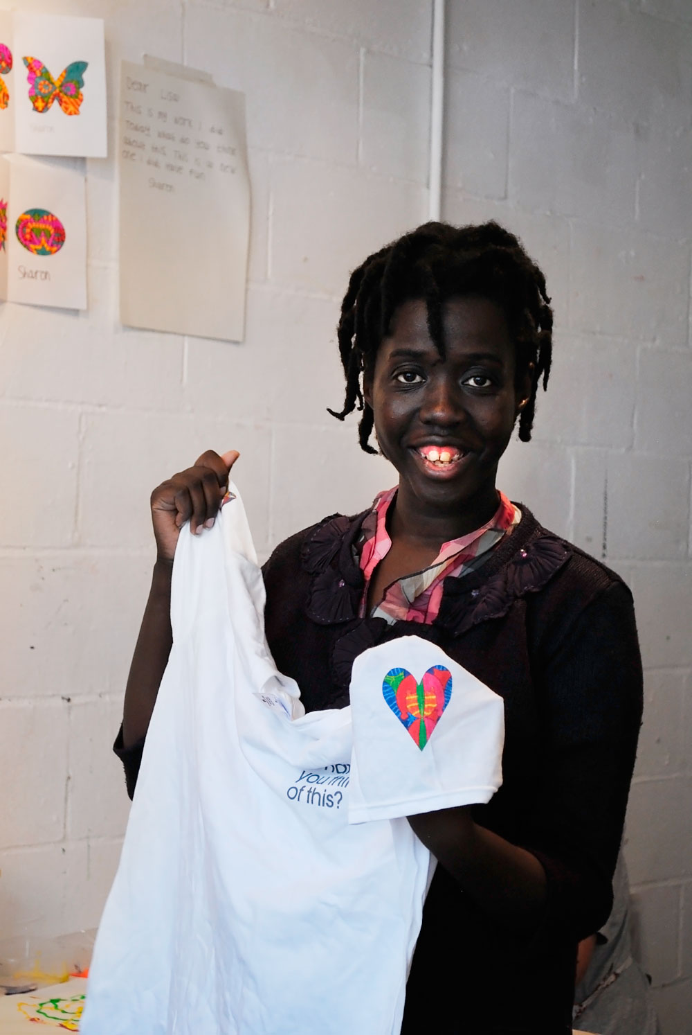 Sharon smiles at the camera, holding a white T-shirt with her illustration on it.